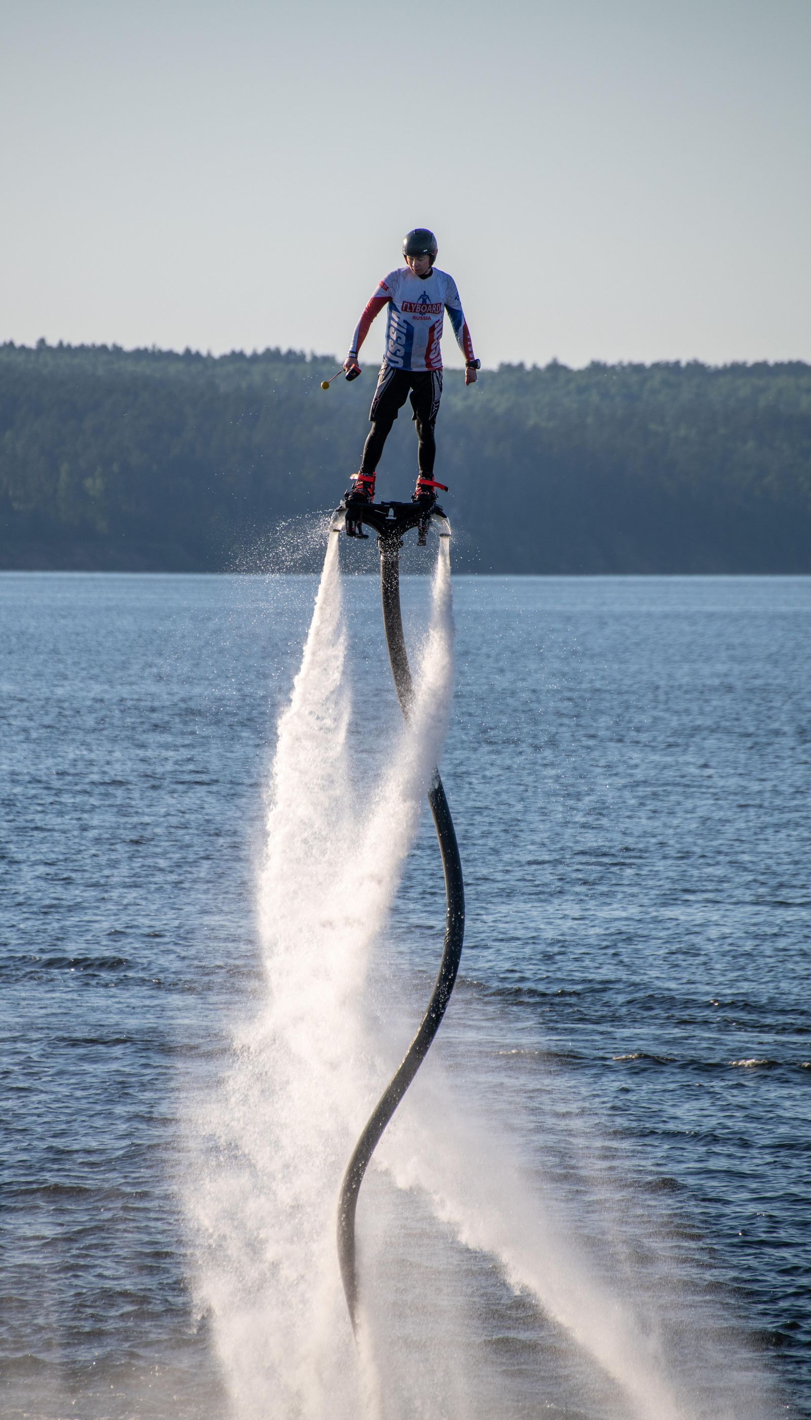 Person flyboarding high above turquoise ocean water