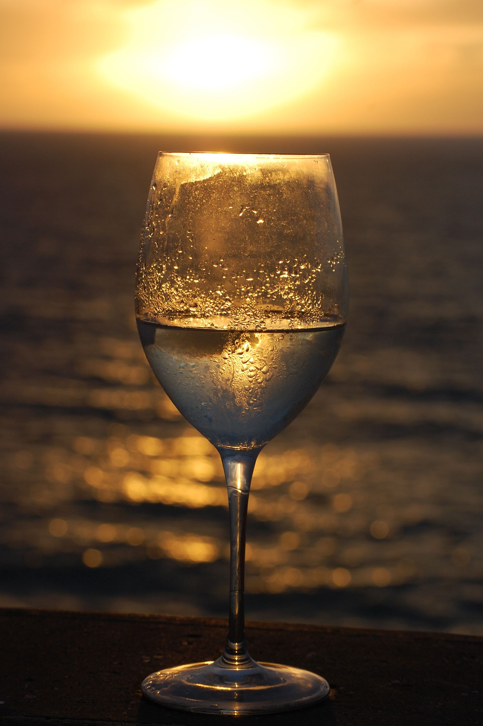 Wine glass catching the sunset light over the ocean